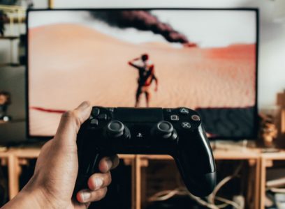 Holding a controller while playing a game on a big-screen TV at home