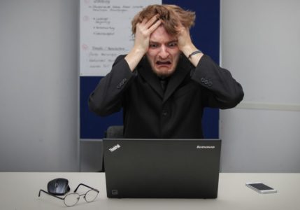 An upset young man sitting before a computer