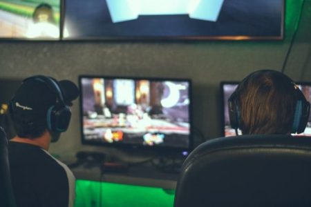 Two people sitting in from of monitors playing games